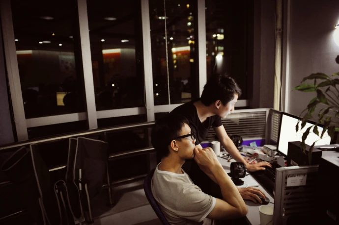 Two men working on computers at night